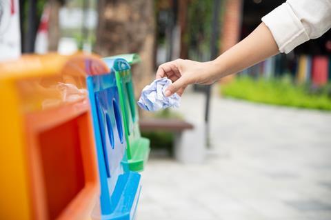 Closeup portrait woman hand throwing crumpled paper in recycling bin.