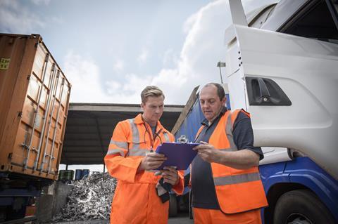 Worker inspecting delivery paperwork with truck driver - Borders and Trade