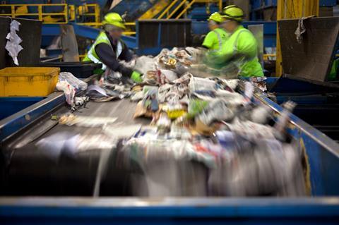 Workers separating paper and plastic on a conveyor belt in a recycling facility Workers separating paper and plastic on a conveyor belt in a recycling facility
